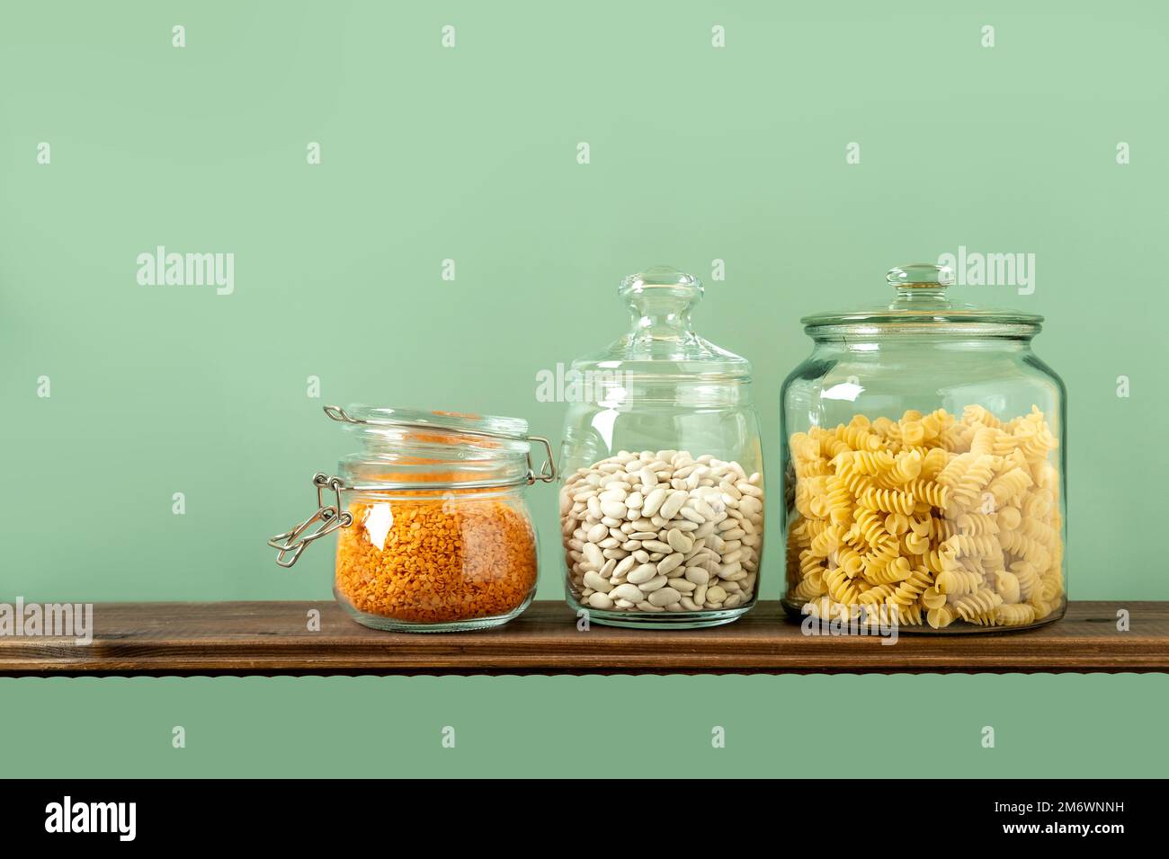 Différentes légumineuses en pots de verre : pâtes, haricots, lentilles sur fond vert. Aucun stockage de déchets, sans plastique. Banque D'Images