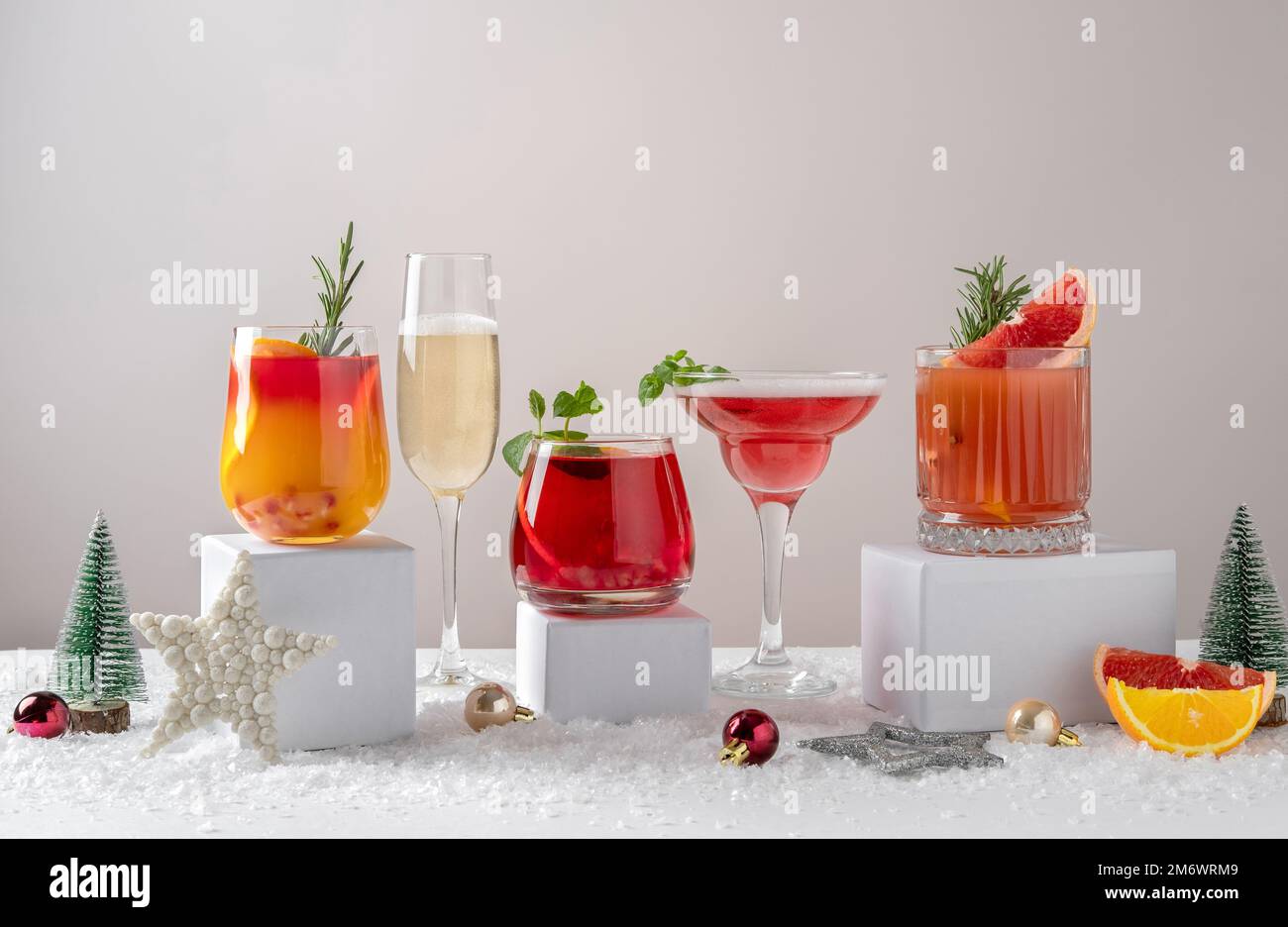 Cocktails d'agrumes festifs sur podiums. Assortiment de boissons fraîches de Noël. Cocktails sangria rose et rouge, champagne, grenade Banque D'Images