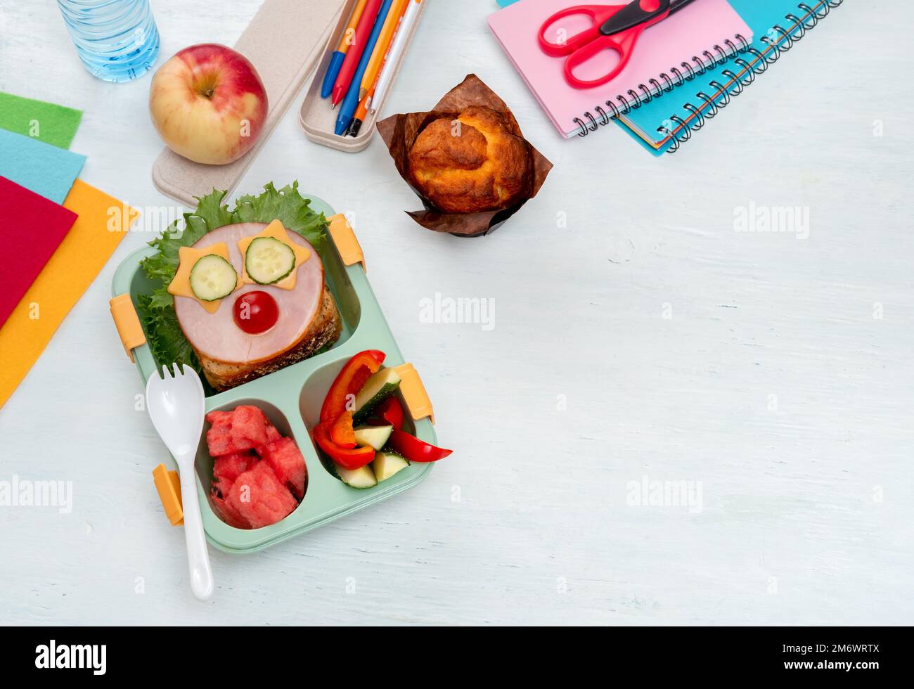 Boîte à lunch d'école pour les enfants avec de la nourriture sous forme de visages drôles. Boîte repas de l'école avec sandwich, légumes, eau et papeterie Banque D'Images