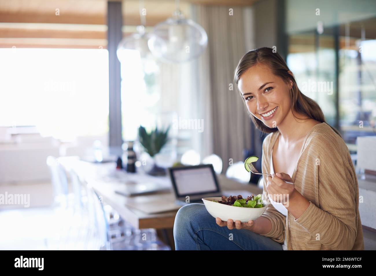 Me fait sentir mieux au sujet du gâteau. Portrait d'une jeune femme heureuse mangeant un bol de salade. Banque D'Images