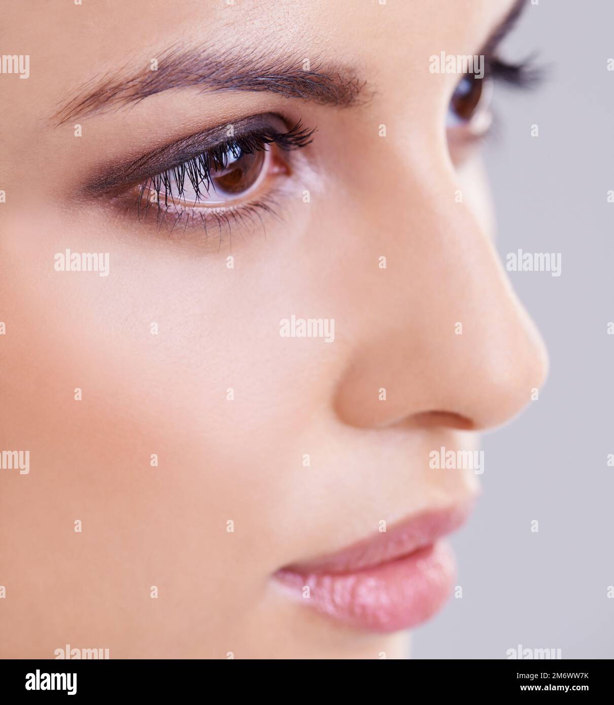 De beaux yeux. Photo studio d'une belle femme brune sur fond gris. Banque D'Images