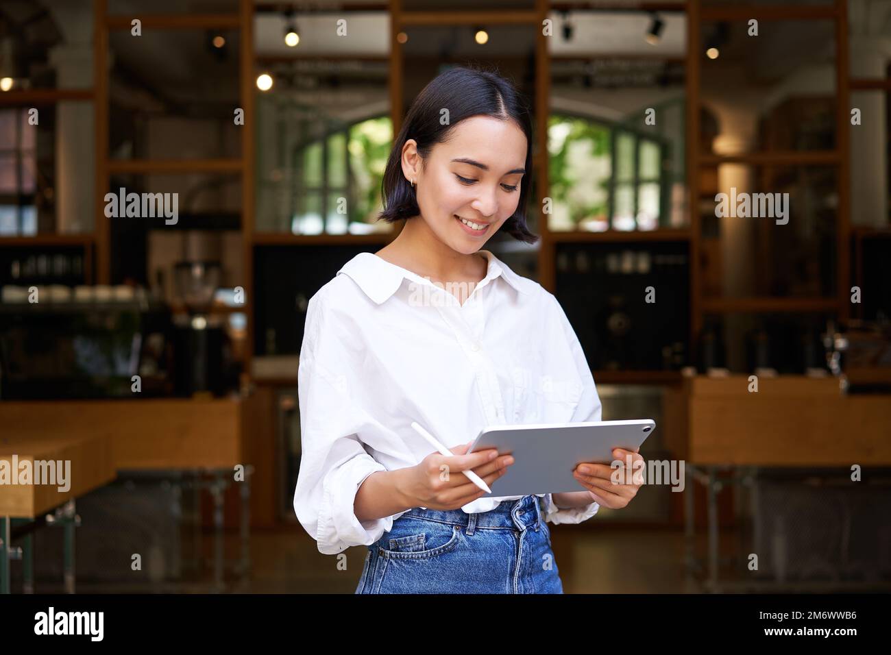 Jeune serveuse asiatique, gérant de café travaillant avec une tablette et une tablette graphique Banque D'Images