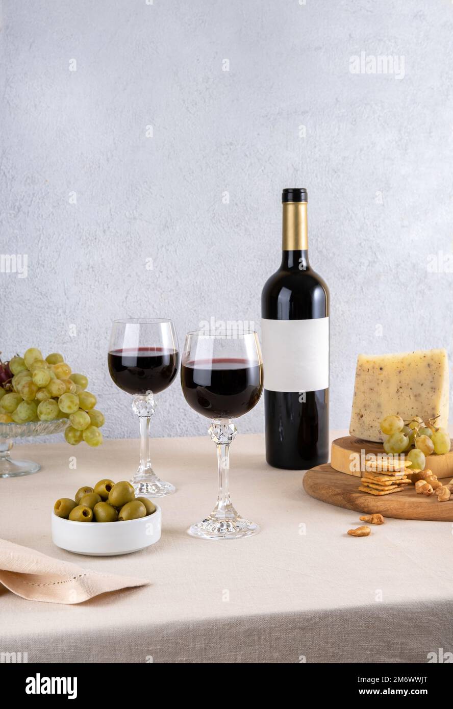 Verre et bouteille de vin rouge avec fromage bleu et raisins sur fond clair. Vin rouge avec fromage et fruits. Bouteille de vin mocku Banque D'Images