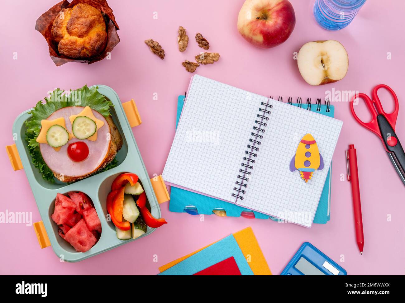 Boîte à lunch d'école pour les enfants avec de la nourriture sous forme de visages drôles. Boîte repas de l'école avec sandwich, légumes, eau et papeterie Banque D'Images