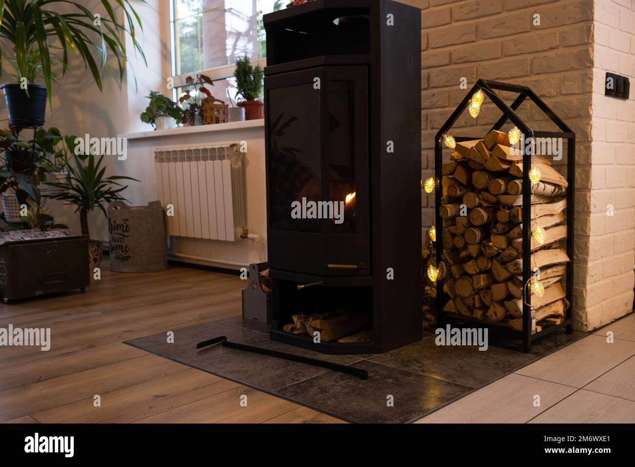 Poêle en métal noir cheminée avec bois dans une pile de bois - l'intérieur d'une maison de village privée. Chauffage et chauffage de la maison Banque D'Images