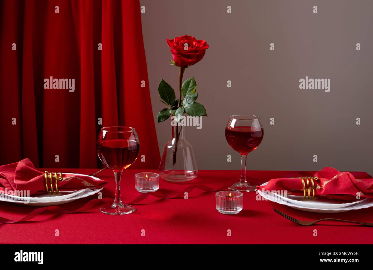 Table romantique avec vaisselle blanche et serviettes rouges, vin et bougies. Concept Saint Valentin ou dîner romantique. Romain Banque D'Images