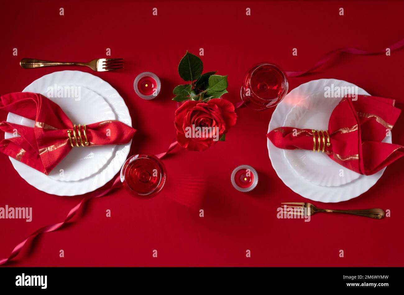 Table romantique avec vaisselle blanche et serviettes rouges, vin et bougies. Concept Saint Valentin ou dîner romantique. Romain Banque D'Images