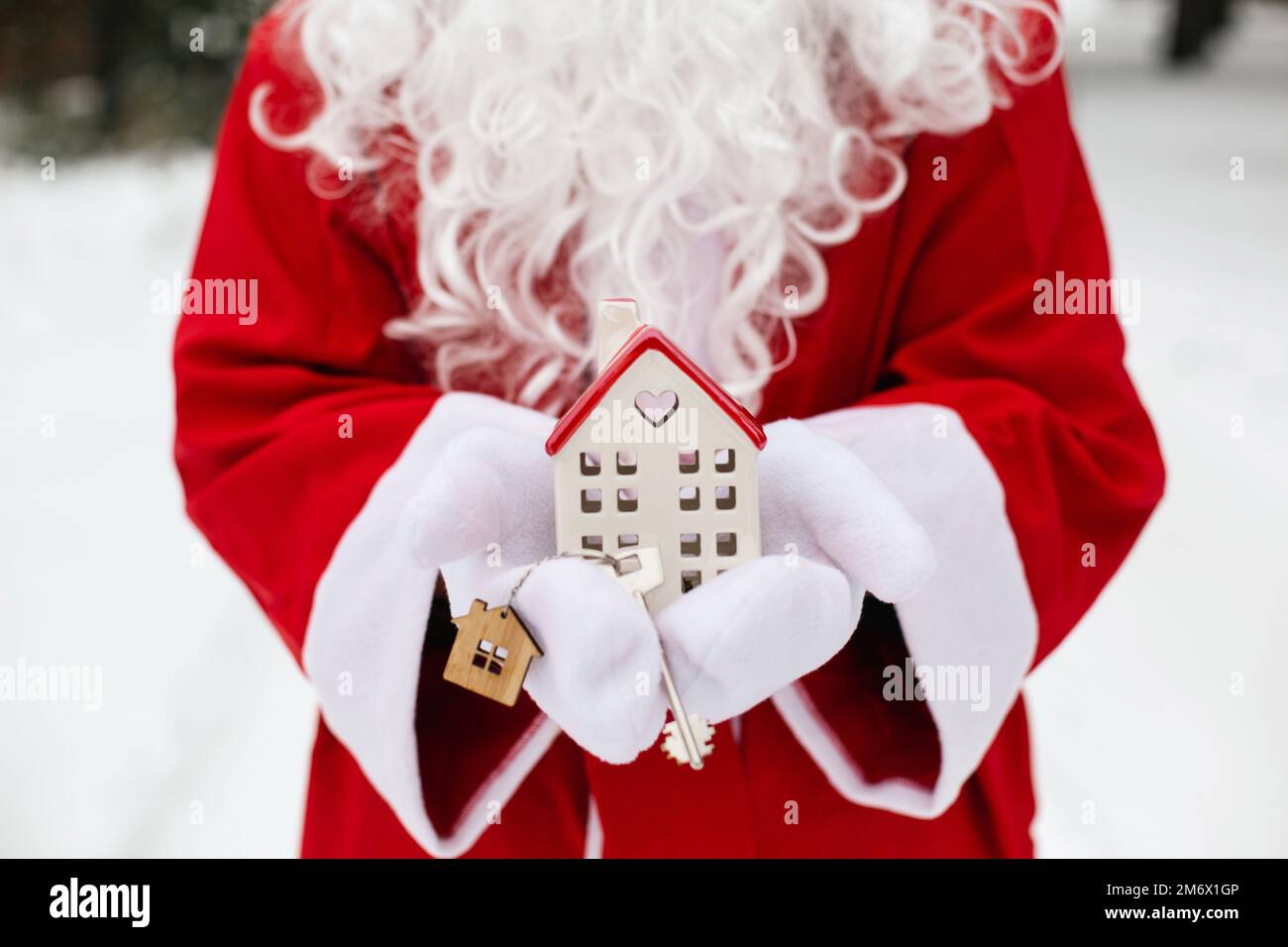 Maison clé avec porte-clés cottage dans les mains du Père Noël extérieur dans la neige. Affaire pour l'immobilier, l'achat, la construction, relocatio Banque D'Images