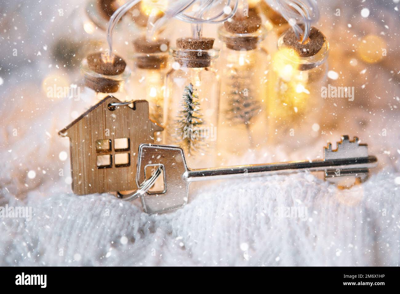 Maison clé avec porte-clés cottage avec lumières de fées dans un pot avec arbre de Noël et neige. Achat, construction, relocalisation, morg Banque D'Images