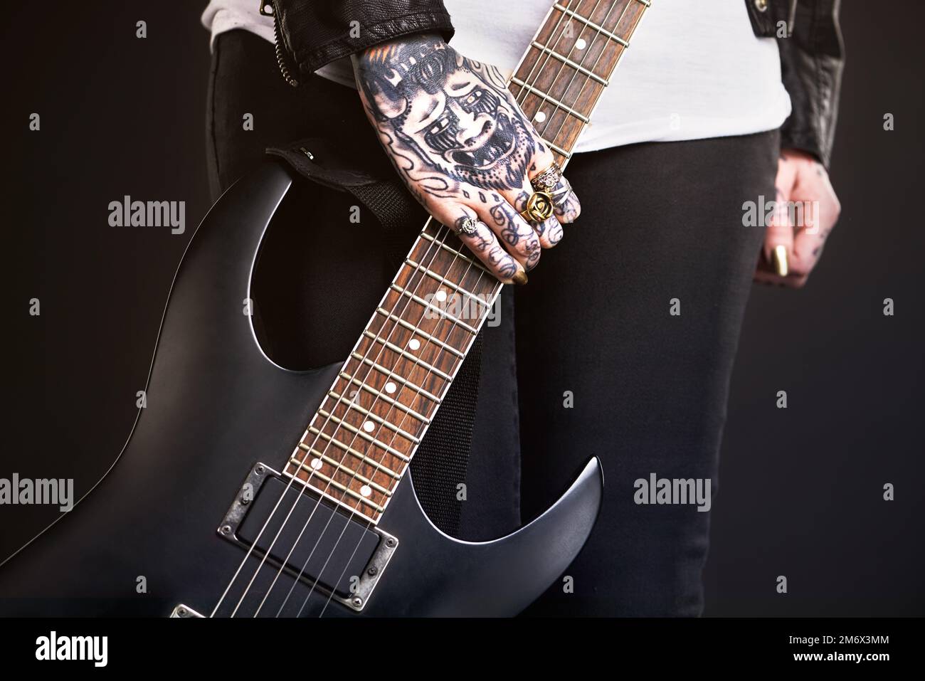 La vie des stars du rock. Photo studio d'un guitariste féminin tatoué. Banque D'Images