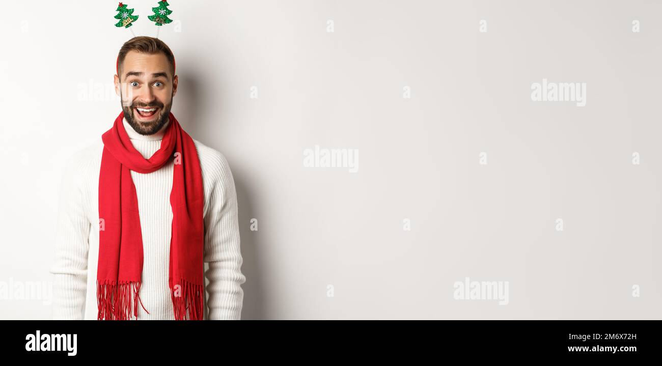 Concept de fête et de célébration de Noël. Heureux barbu homme regardant surpris, portant drôle accessoire chapeau, debout contre le coup Banque D'Images