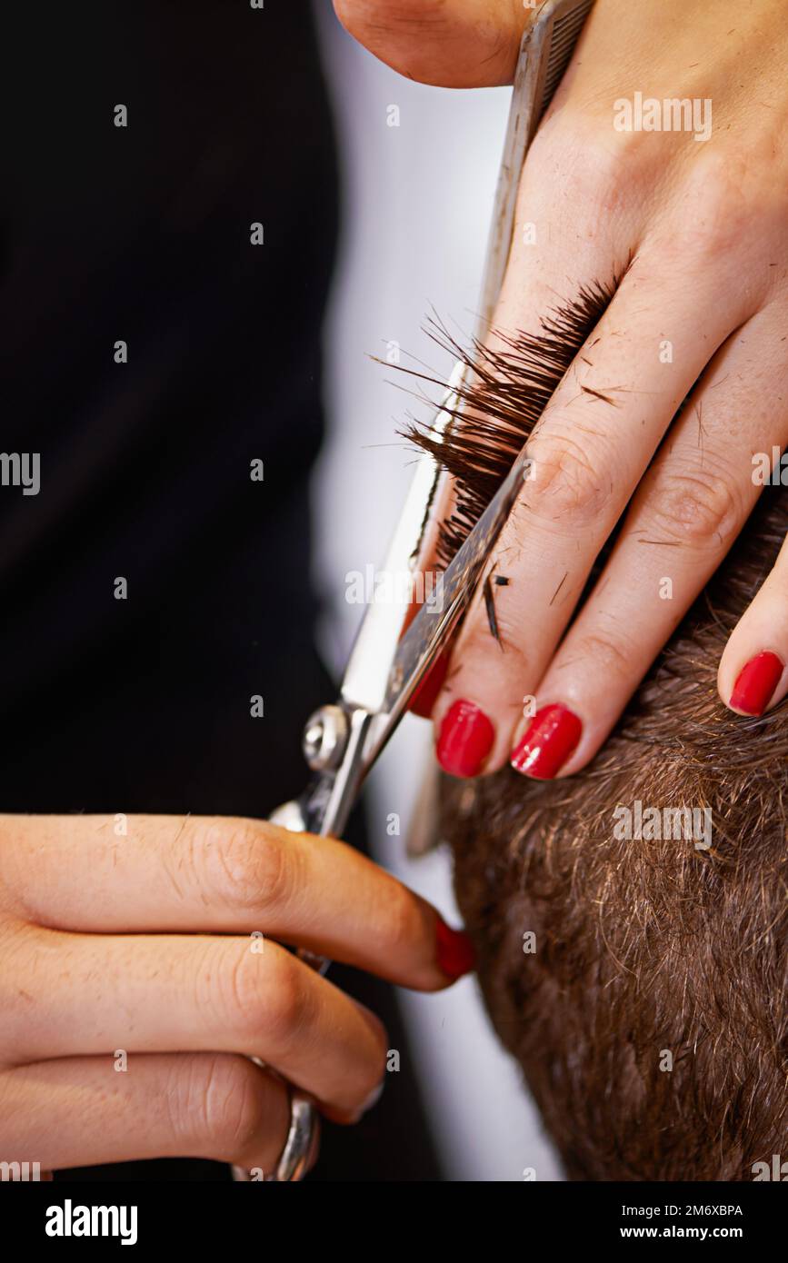 Ciseaux maniés par un professionnel. Gros plan d'une personne ayant ses cheveux coupés dans un salon de coiffure. Banque D'Images