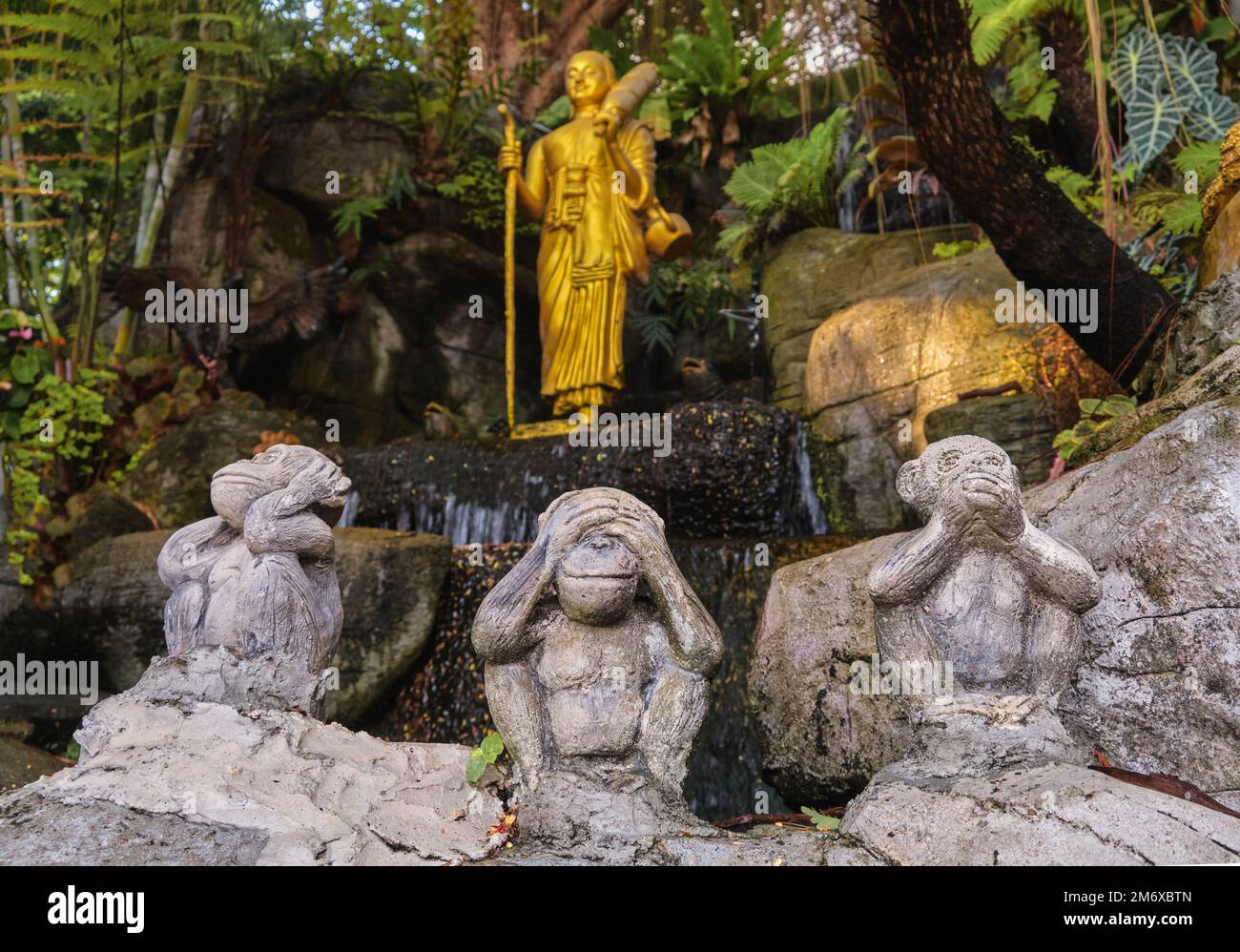 Symboles du bouddhisme : Bouddha comme moine de marche et trois statues de singes sages. Banque D'Images