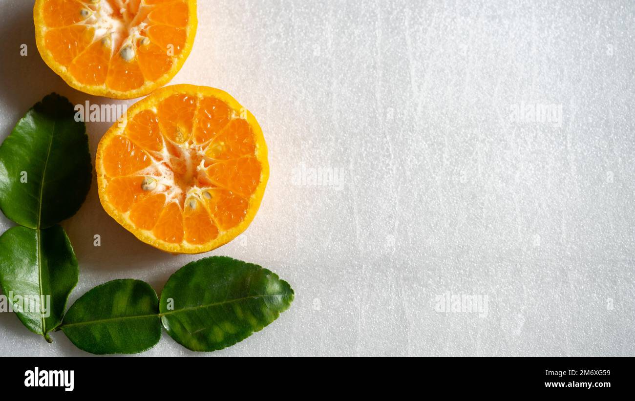 Orange coupé en deux et feuilles vertes isolées sur fond blanc Banque D'Images