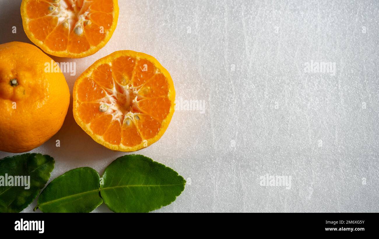 Orange coupé en deux et feuilles vertes isolées sur fond blanc Banque D'Images