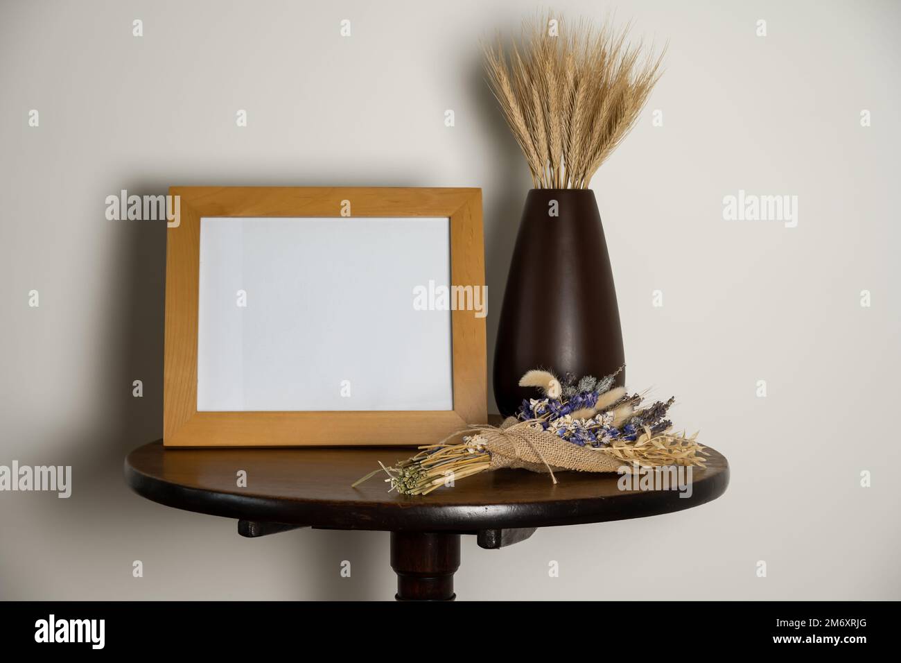 maquette style de vie table de piédestal intérieur avec cadre photo vase vide de feuilles de blé séchées et fleurs séchées sur la table Banque D'Images