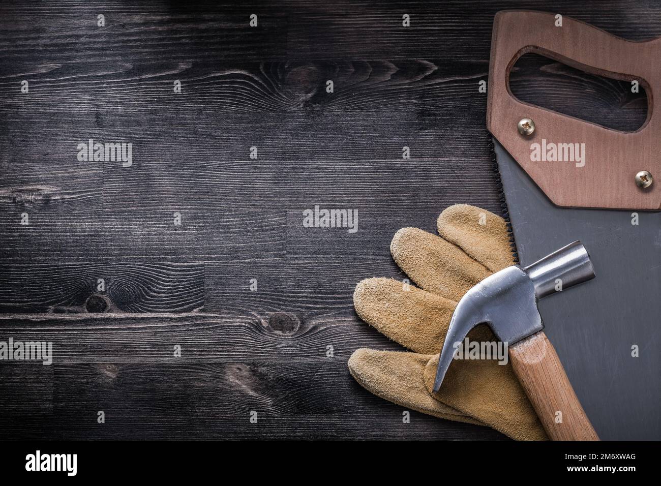 Griffe de scie à métaux avec marteau gants de protection en cuir sur panneau de bois. Banque D'Images