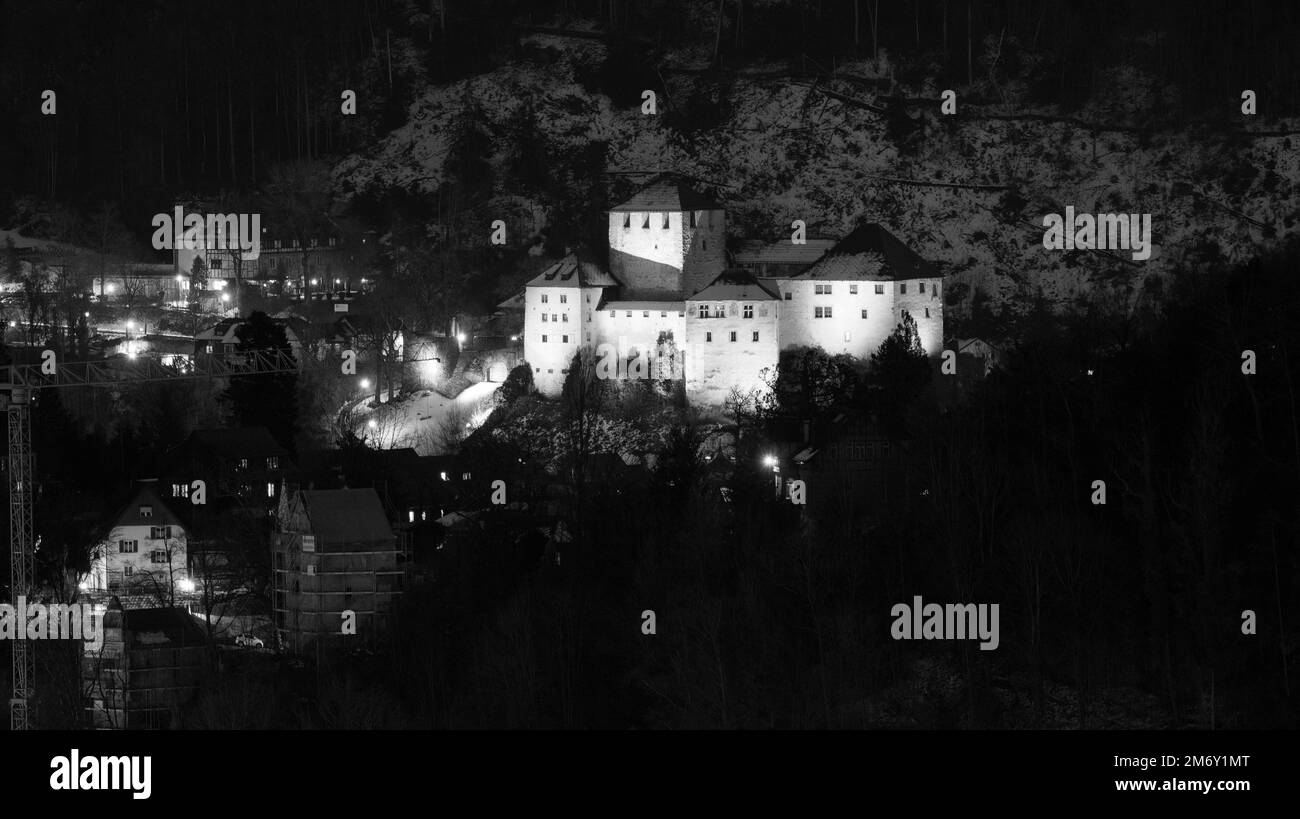 Château de Schattenburg à Feldkirch, Autriche la nuit en noir et blanc avec des travaux de construction à côté et de la neige sur la colline derrière elle Banque D'Images