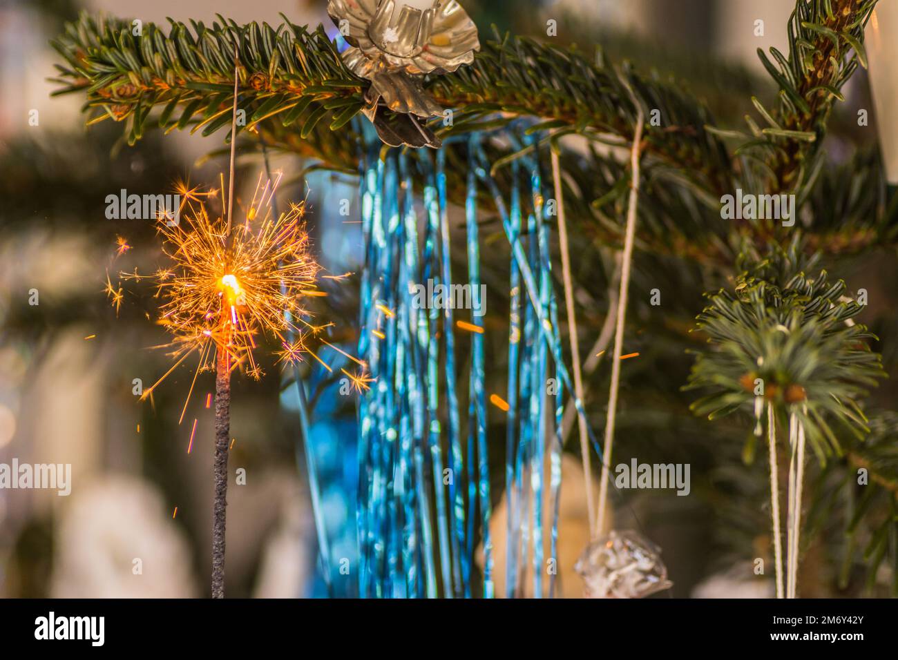 guirlande bleue et un flambeau avec beaucoup d'étincelles à l'arbre de noël Banque D'Images