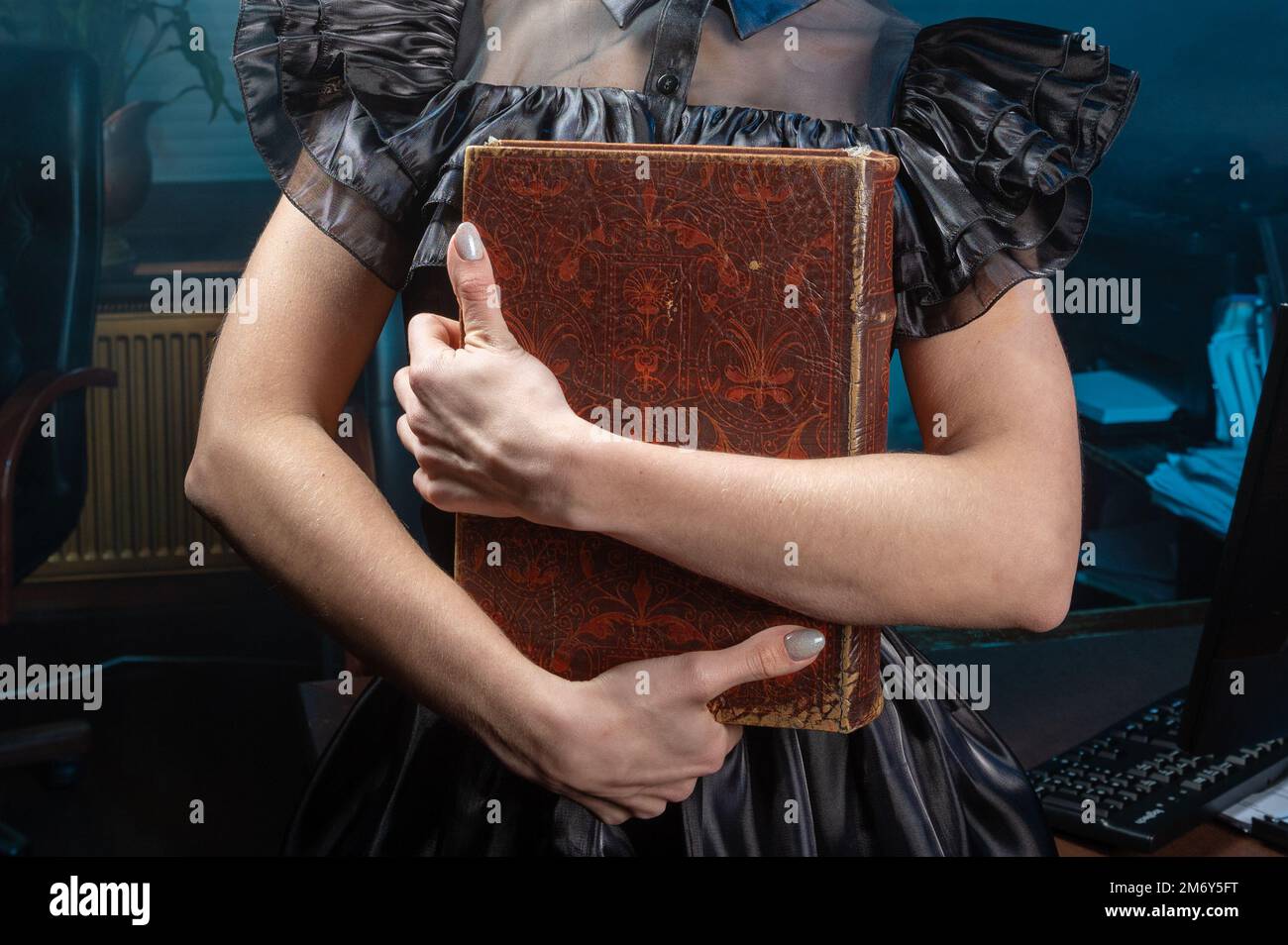 Vieux livre dans les mains de femme gros plan. Femme tient un livre antique dans ses mains. Livre fermé avec pages anciennes. Banque D'Images