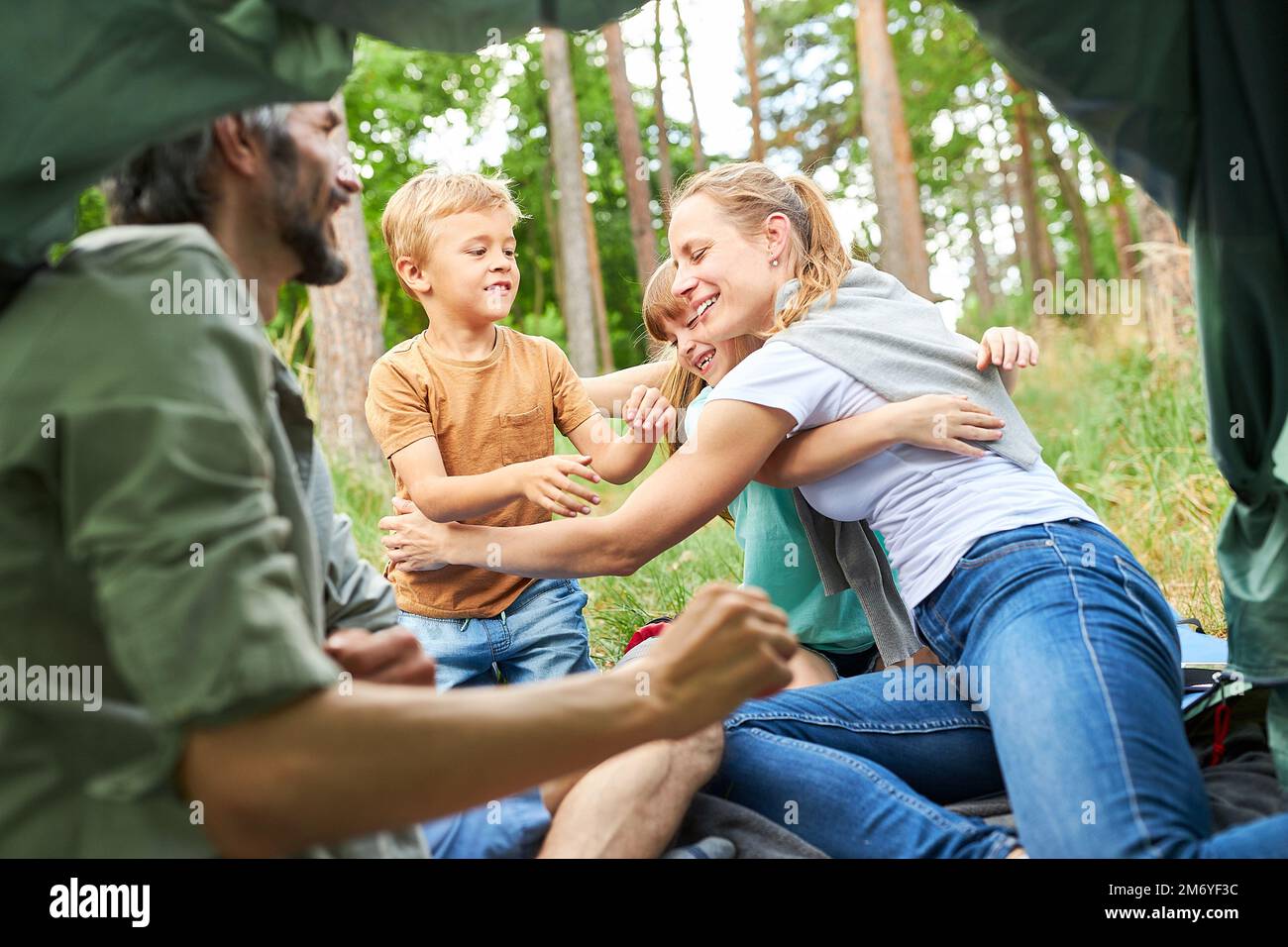 Une mère heureuse embrassant sa fille et son fils tout en s'asseyant dans une tente pendant la forêt Banque D'Images