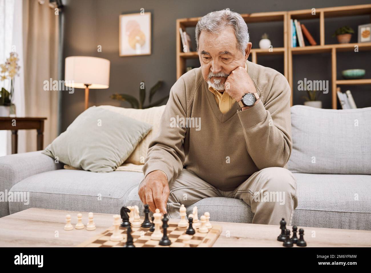 Homme senior, pensant ou jouant aux échecs dans la maison, salon ou appartement à la maison dans la stratégie japonaise, chéquier ou jeu de société concours. Retraite Banque D'Images