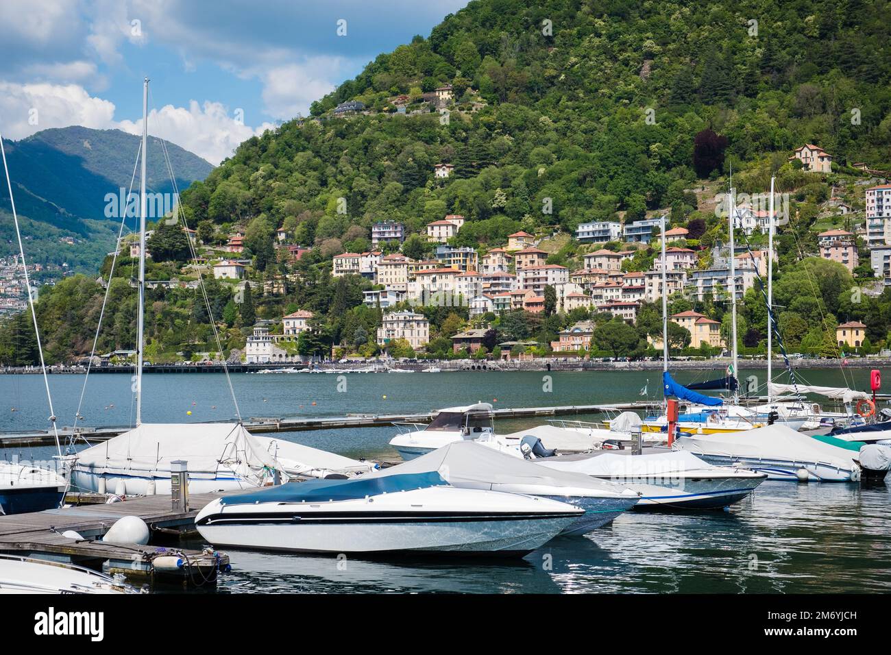 Como, Italie - 1 mai 2022: Paysage et paysage autour du lac de Côme dans le nord de l'Italie avec une rangée de petits bateaux sur l'eau. Banque D'Images