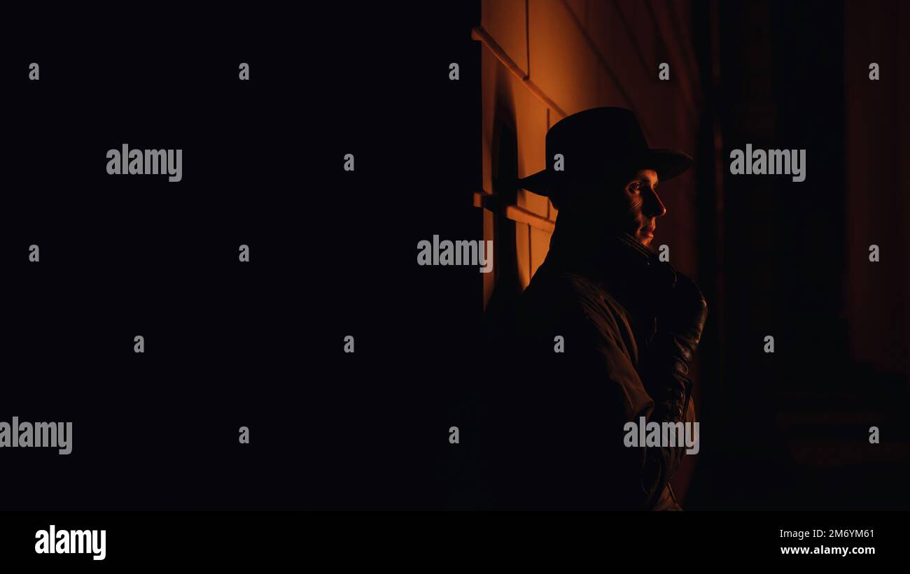 un détective mafieux masculin dans un chapeau et un imperméable la nuit dans le style de film noir Banque D'Images