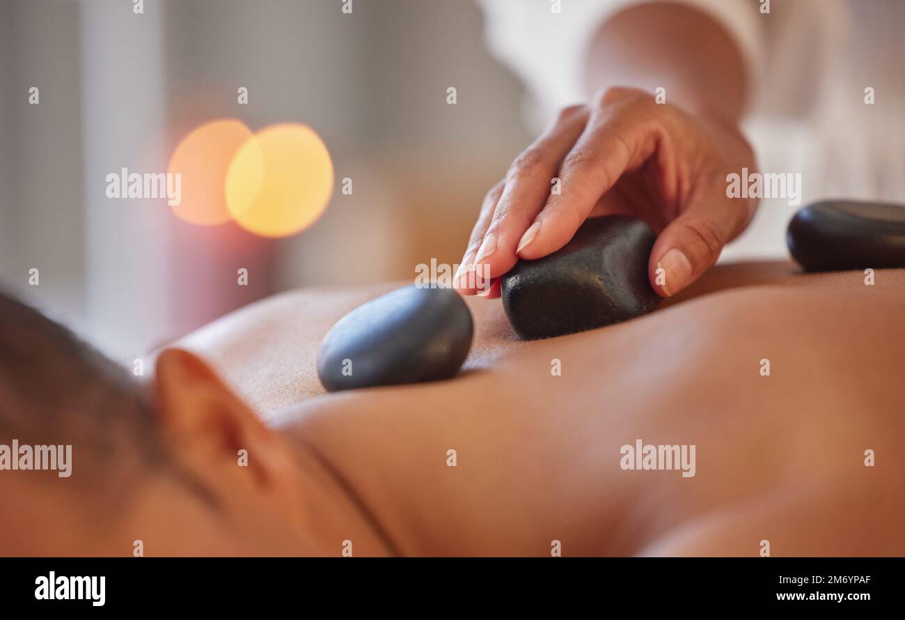 Spa, massage homme et pierre pour se détendre, bien-être et santé pour les soins du corps, la paix ou les soins holistiques. Homme, homme ou allongé sur une table dans un complexe de luxe Banque D'Images