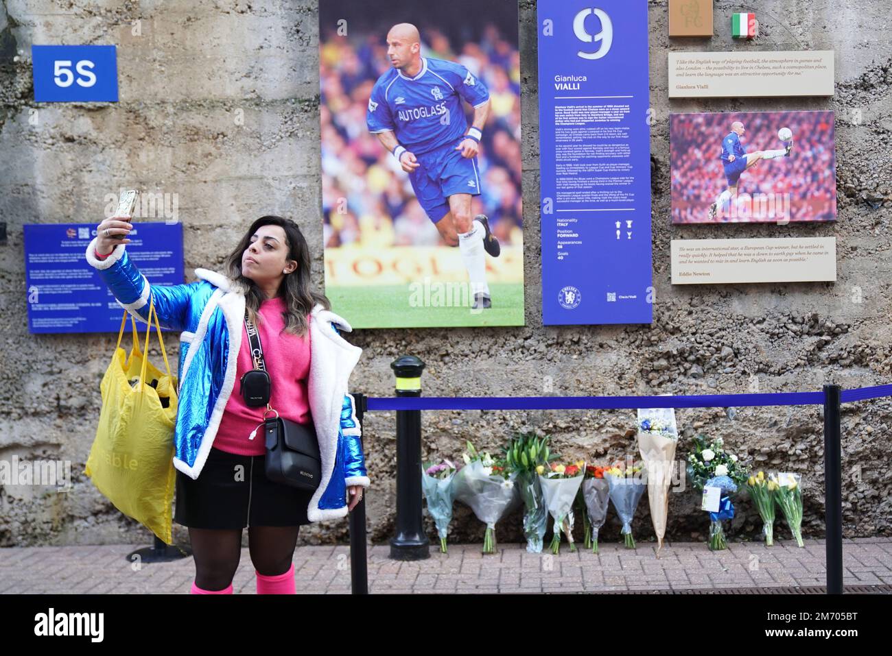 Une femme prend un selfie par des fleurs et des hommages par des photos de Gianluca Vialli sur le mur de la renommée de Chelsea au Stamford Bridge Ground du club, Londres, après l'annonce de la mort de l'ancienne Italie, Juventus et le percuteur de Chelsea, qui est décédé à l'âge de 58 ans après une longue bataille contre le cancer du pancréas. Date de la photo: Vendredi 6 janvier 2023. Banque D'Images