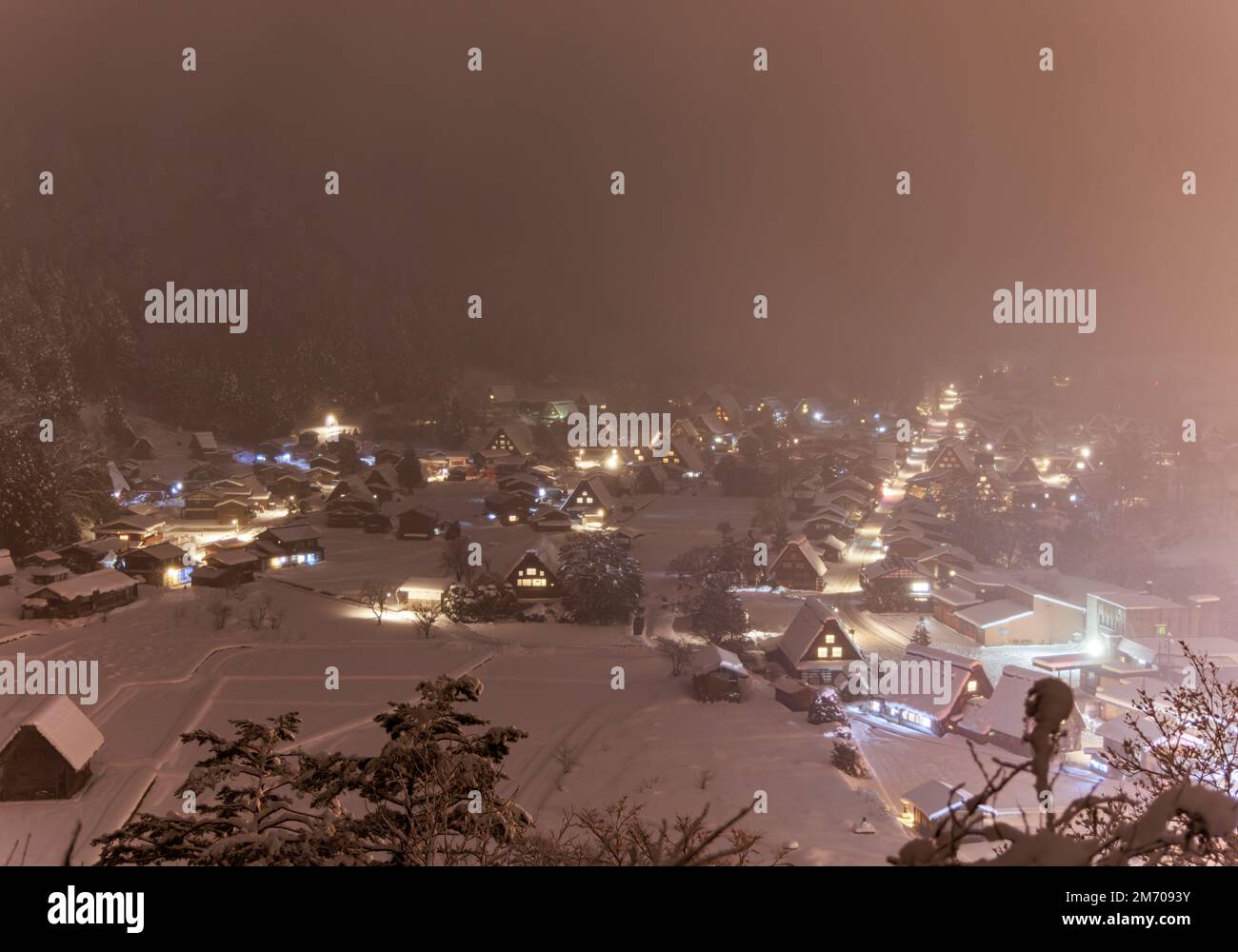 Les maisons Shirakawa-Go baignaient dans la brume de neige rose la nuit d'hiver Banque D'Images