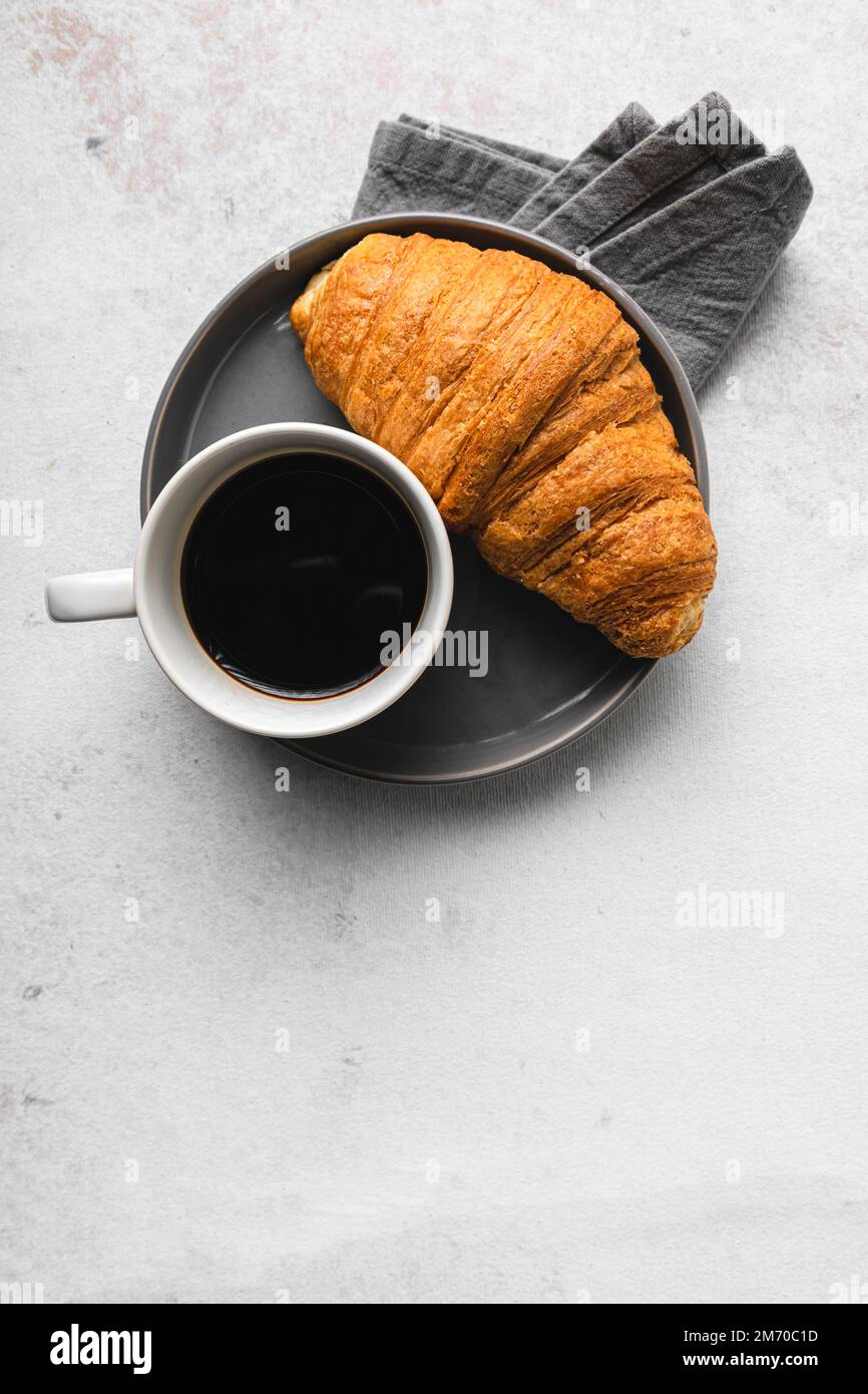 Une tasse de café et un croissant sur une table Banque D'Images