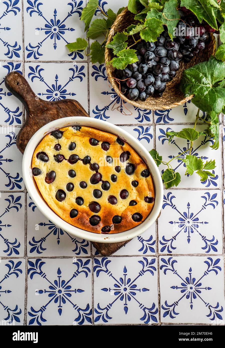 Clafoutis de raisin rouge, cuisine française. sur une table en carreaux de céramique avec un motif bleu. Banque D'Images