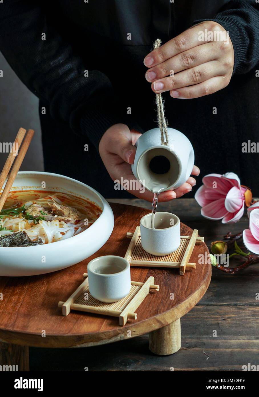 Composition de saké japonais avec soupe asiatique avec nouilles de riz, cérémonie de repas asiatique avec fleurs de magnolia Banque D'Images