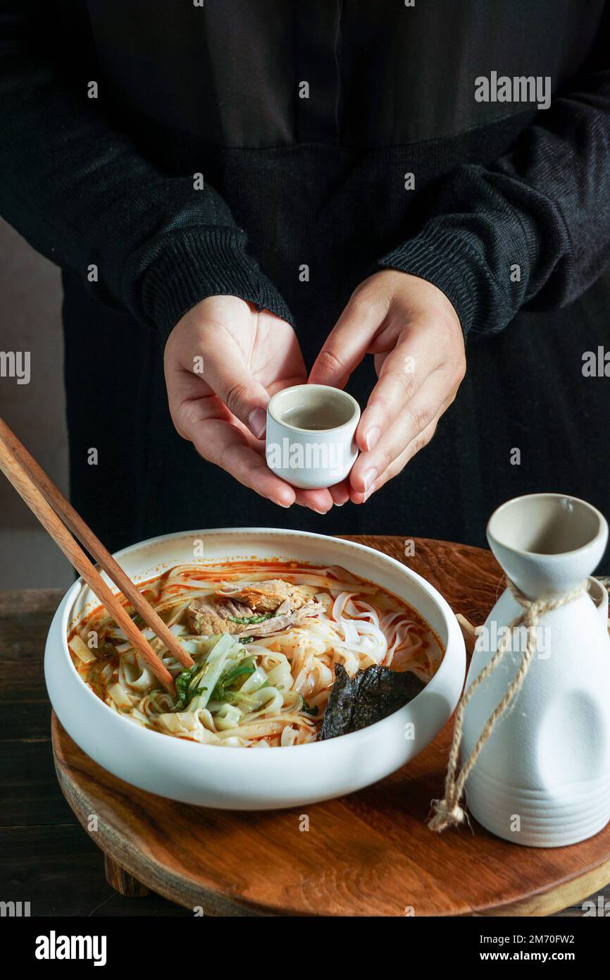 Composition de saké japonais avec soupe asiatique avec nouilles de riz, cérémonie de repas asiatique avec fleurs de magnolia Banque D'Images