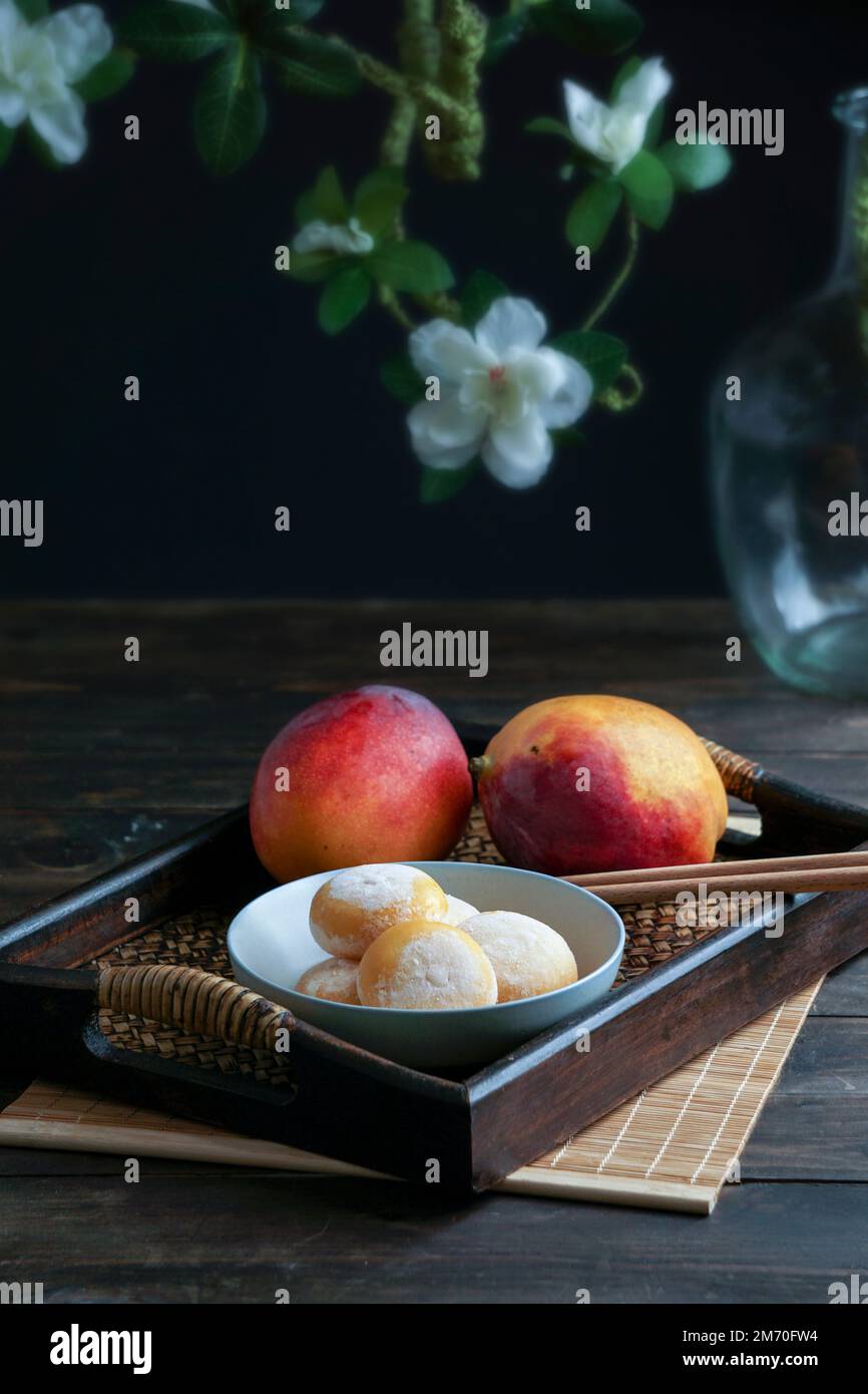 des gâteaux japonais de mochi à la mangue avec de la crème glacée sur un plateau asiatique classique en bois Banque D'Images