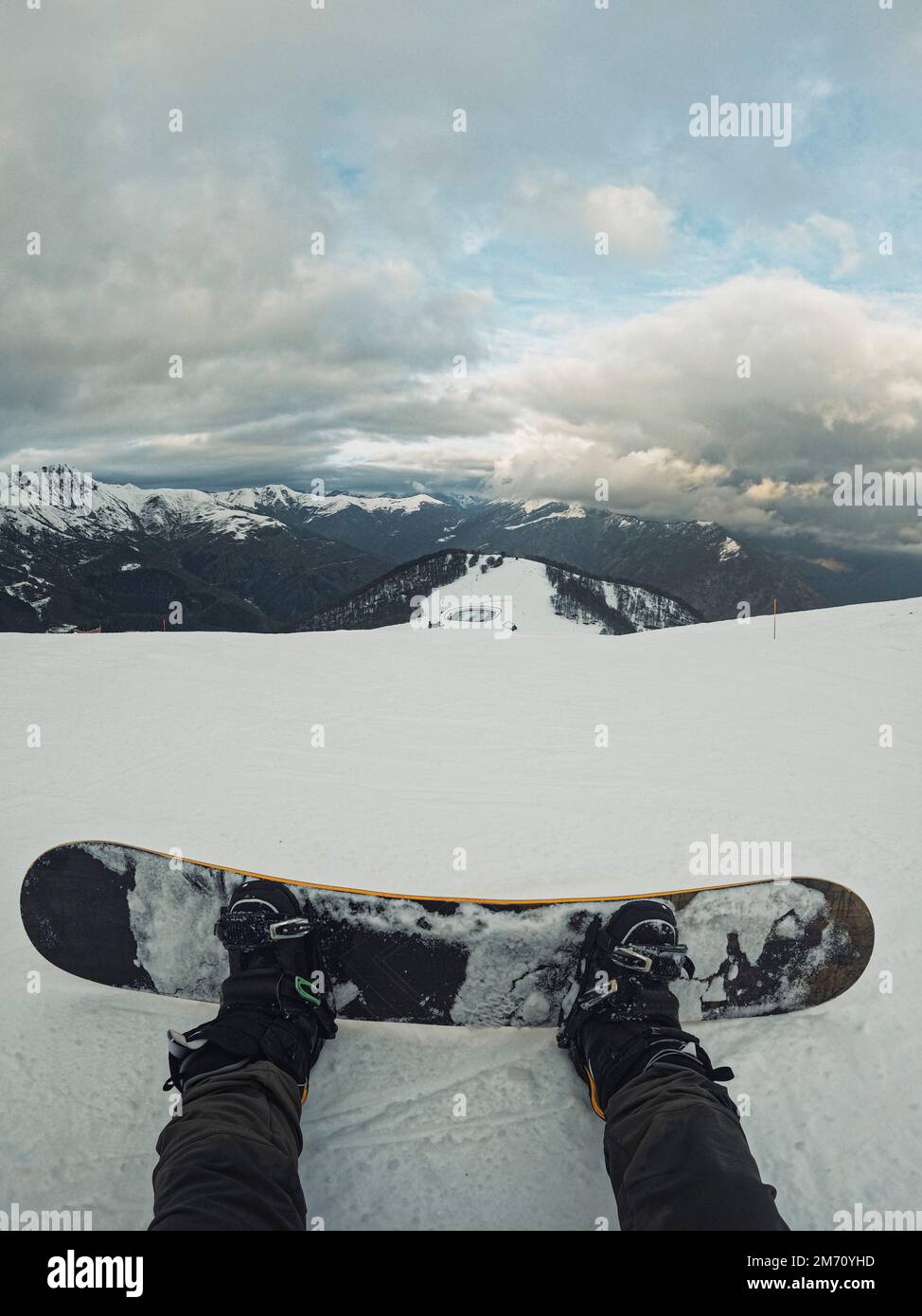 Homme de POV vertical reposant sur la neige avec surf des neiges appréciant et admirant le paysage panoramique. Concept de vacances d'hiver montagnes et actif Banque D'Images