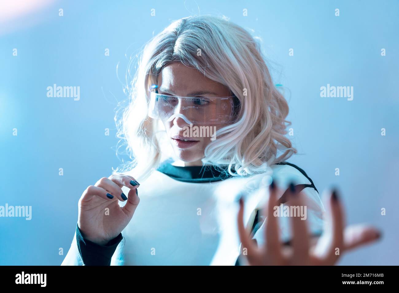 Femme avec les lunettes futuristes illuminées et les cheveux blancs, réalité virtuelle avec regarder sur les côtés Banque D'Images