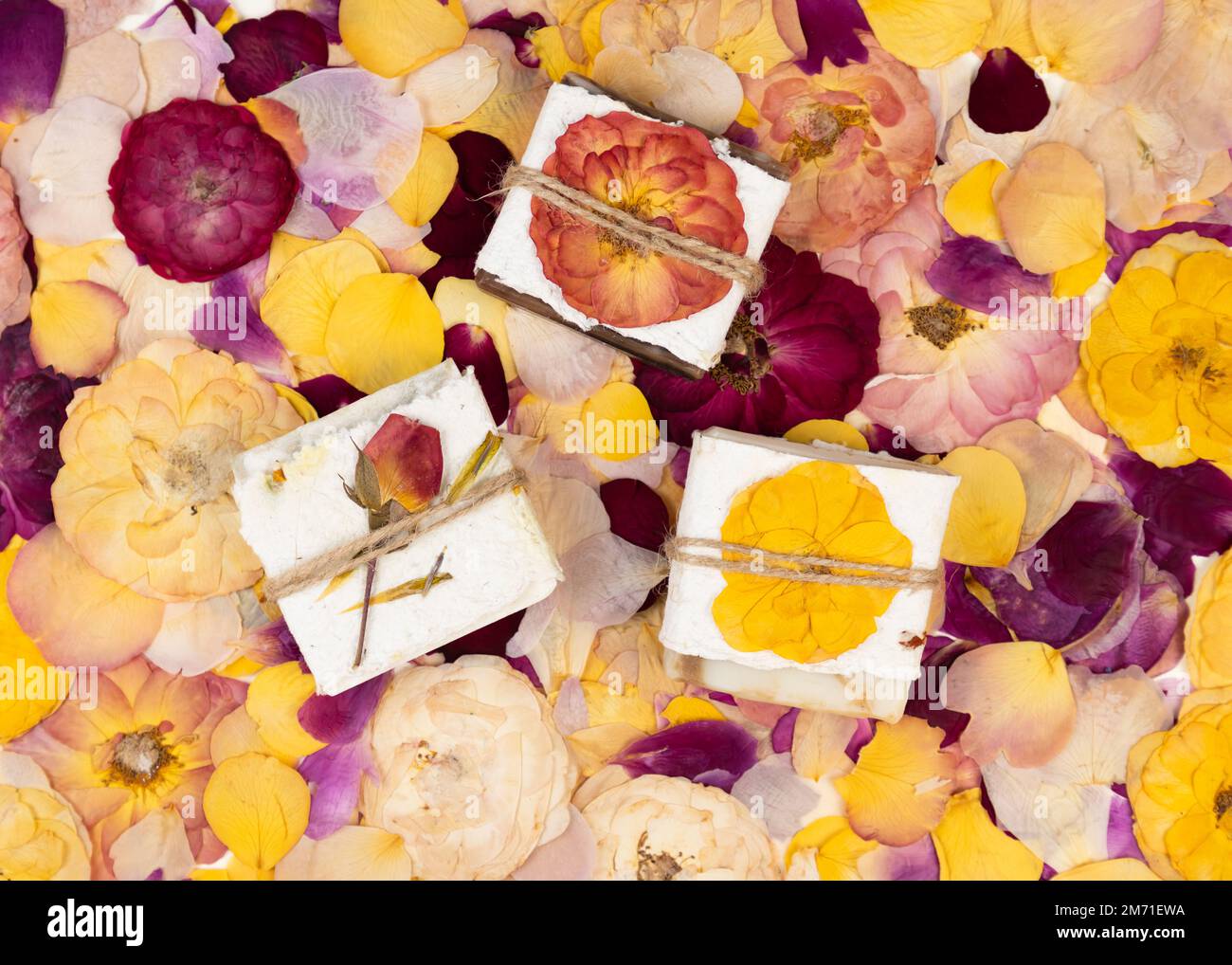 Le savon naturel fait maison, enveloppé de papier à fleurs pressé fait main, repose sur des pétales de rose. Idée de cadeau d'entreprise ou personnelle. Cadeau pour la Saint-Valentin pour Femme Banque D'Images