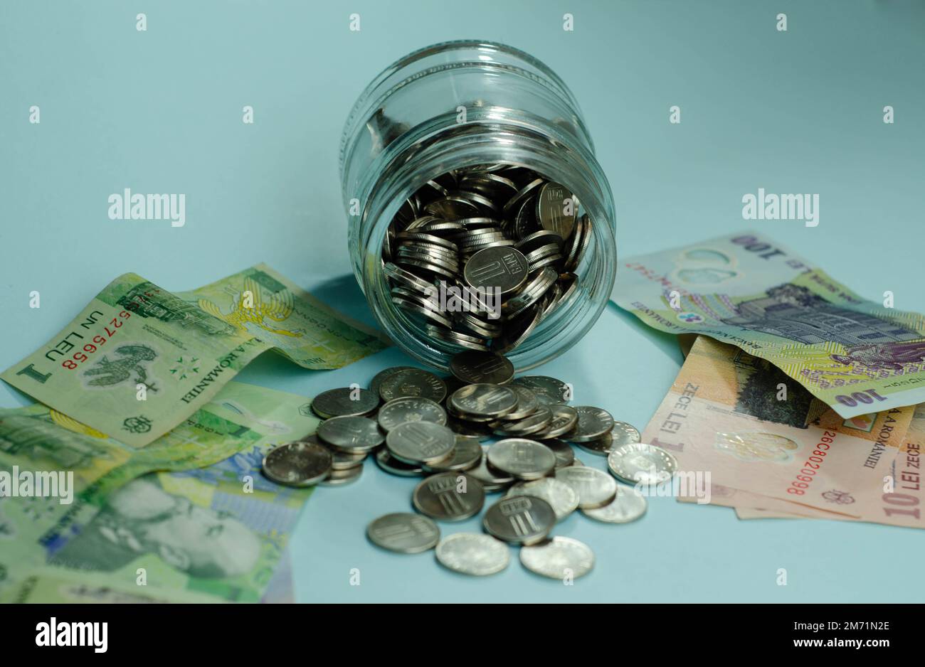 Pots en verre avec pièces de monnaie , isolé - concept d'épargne. Billets de banque roumains, concept économique et financier, hausse des prix, valeur du leu roumain Banque D'Images