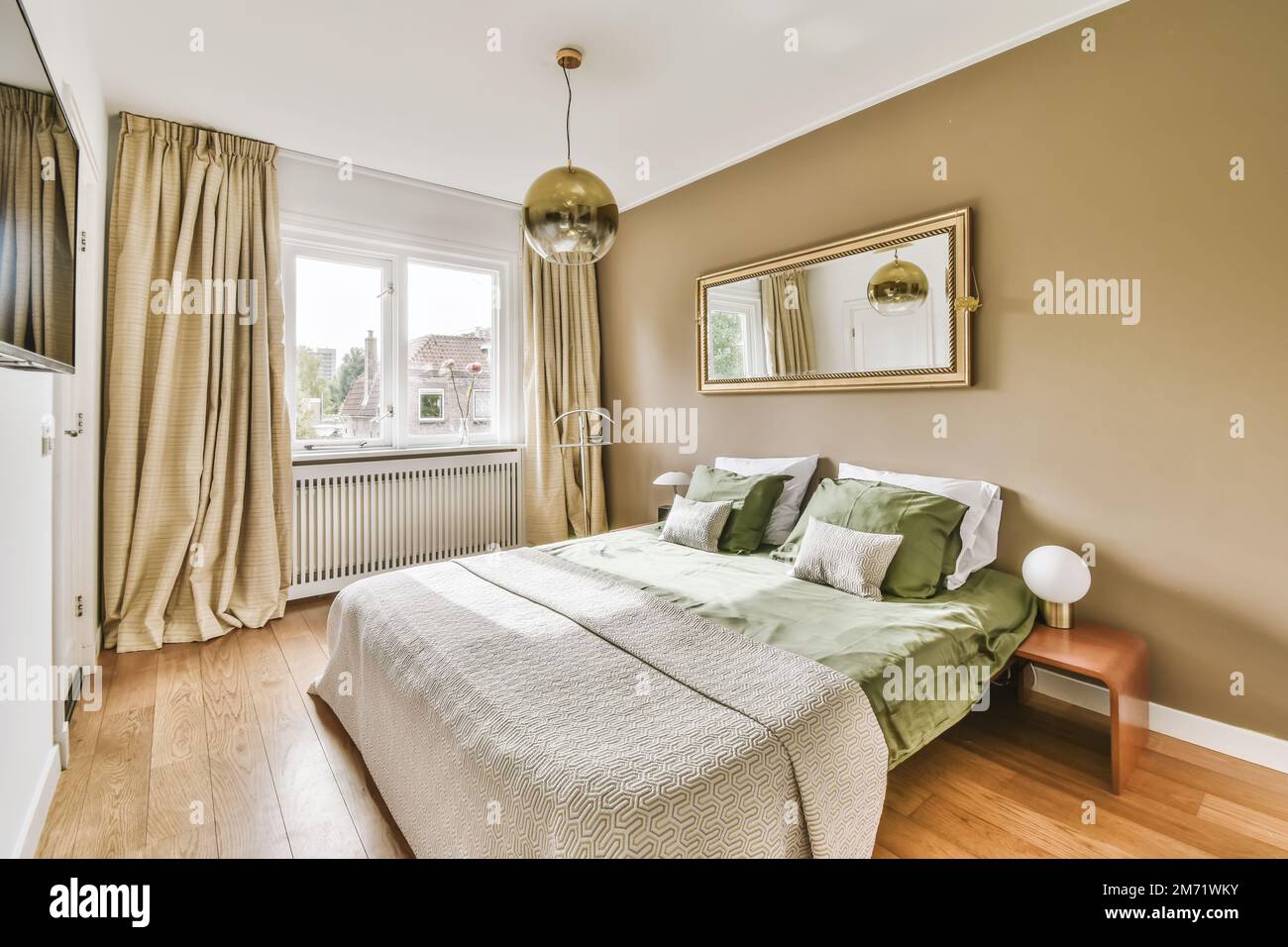 une chambre avec un lit, une commode et un miroir sur le mur en face du lit il y a un parquet Banque D'Images