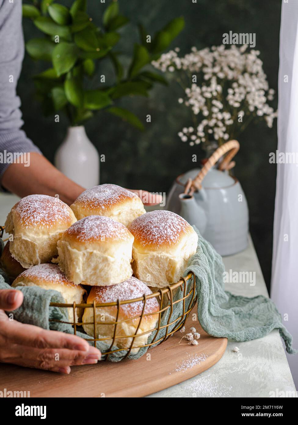 Petits pains faits maison au lait et au fromage à la crème dans un panier avec un chiffon à côté d'une fenêtre Banque D'Images
