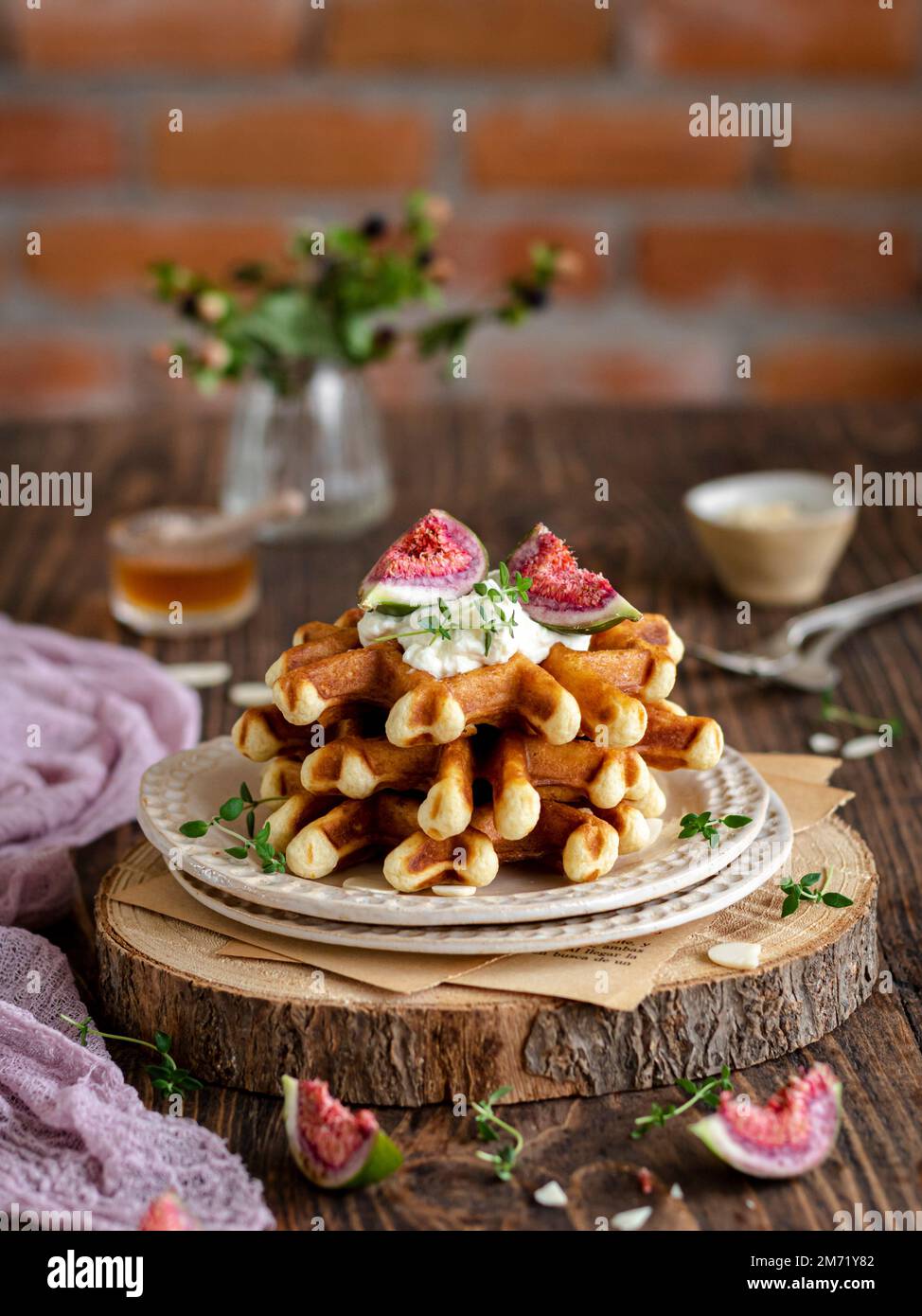 Pile de gaufres avec figues, crème, thym et miel sur un panneau rustique en bois. Banque D'Images