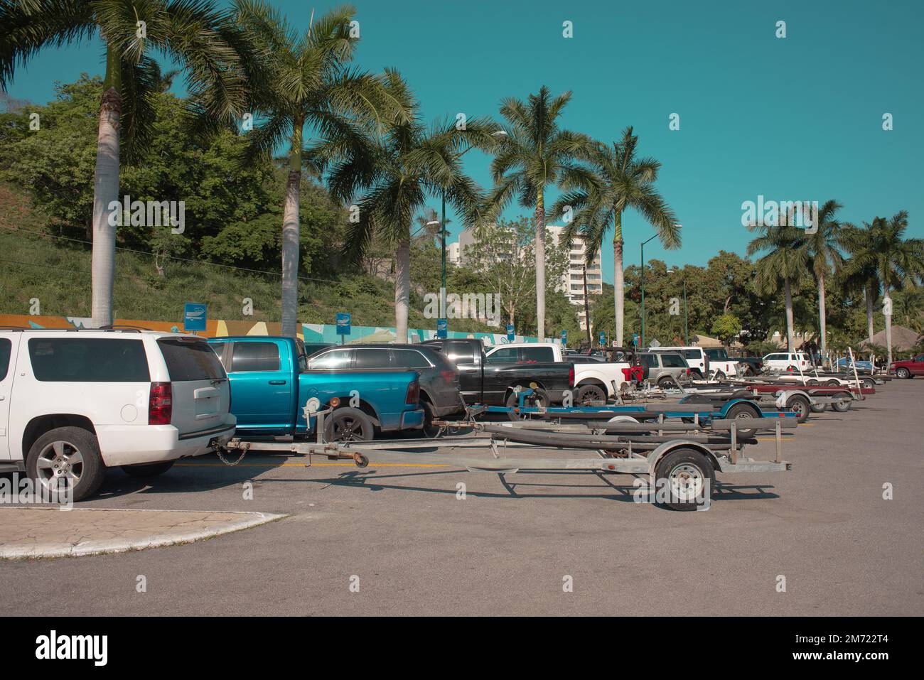 remorque-bateau parking camion plein de véhicules pendant une journée d'été sans personne, palmiers en arrière-plan, ciel bleu Banque D'Images