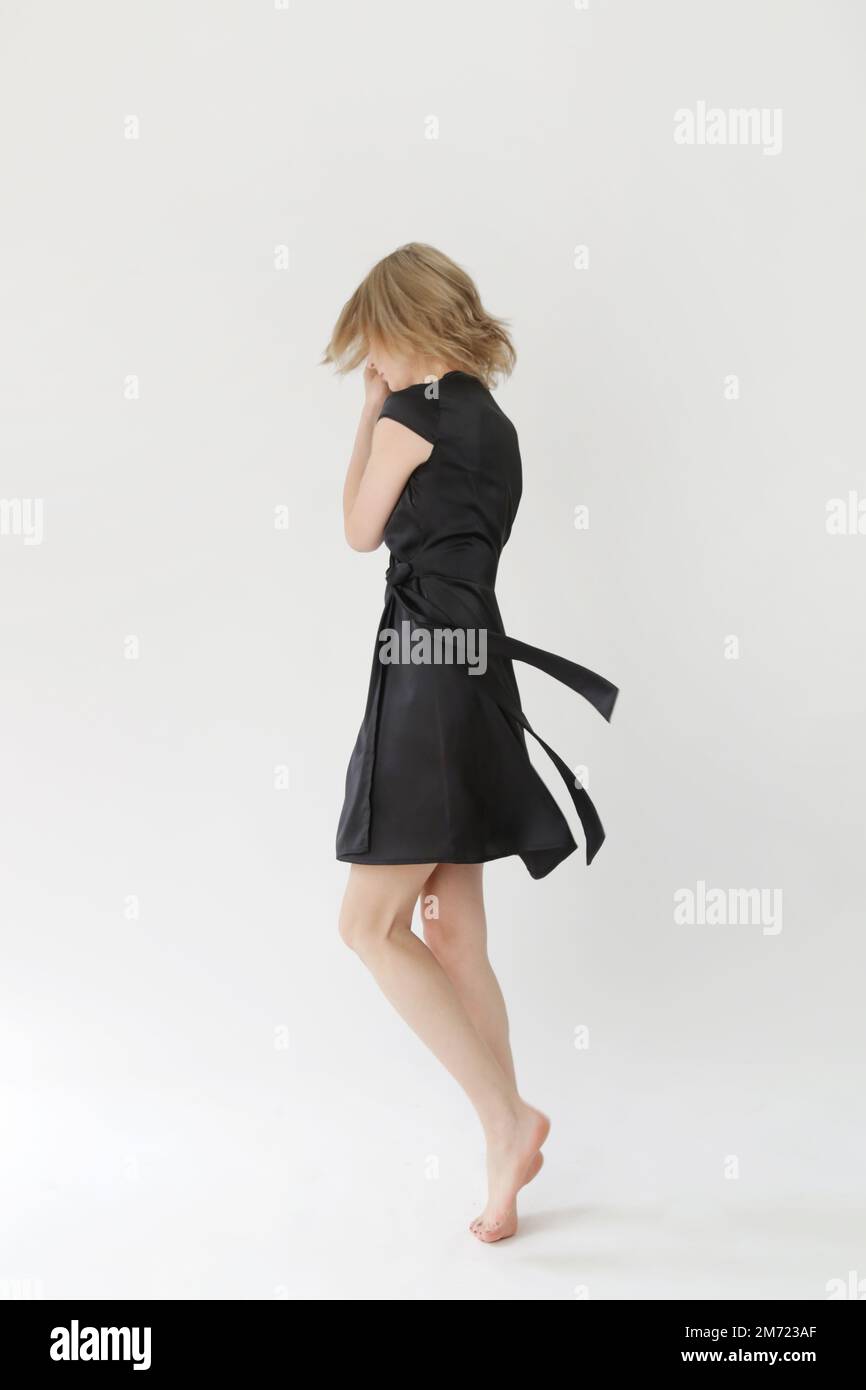 Série de photos de studio de jeune femme modèle en soie noire satin envelopper mini robe. Banque D'Images