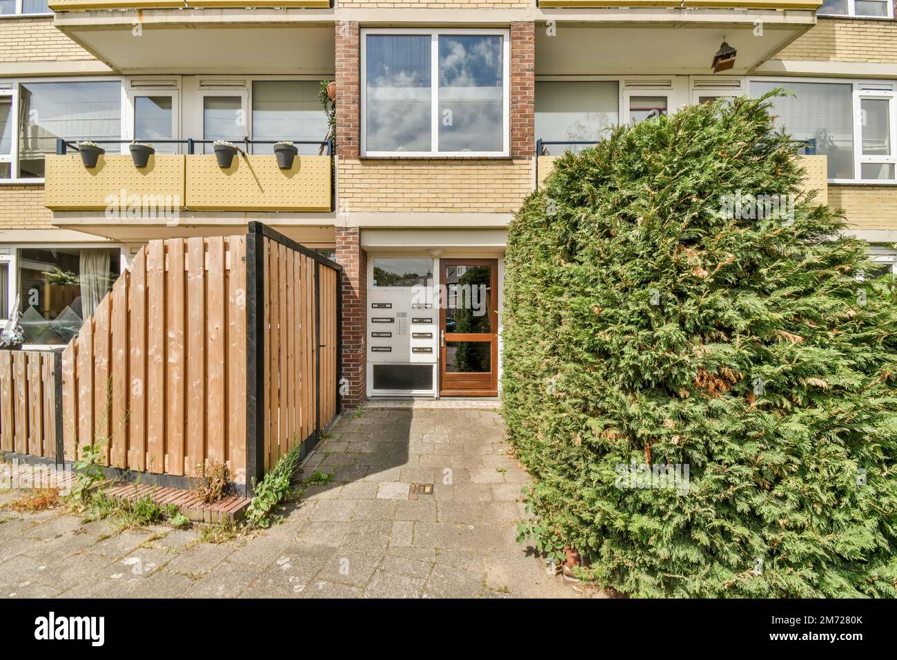 vue extérieure d'une maison de deux étages avec arbres et buissons dans la cour avant, entourée d'arbustes Banque D'Images