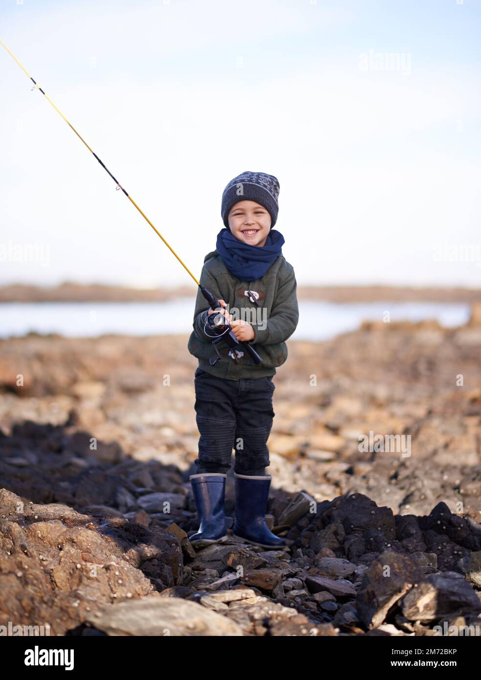 Je vais les capturer tous. Portrait d'un petit garçon mignon tenant une canne à pêche en se tenant au bord de la mer. Banque D'Images