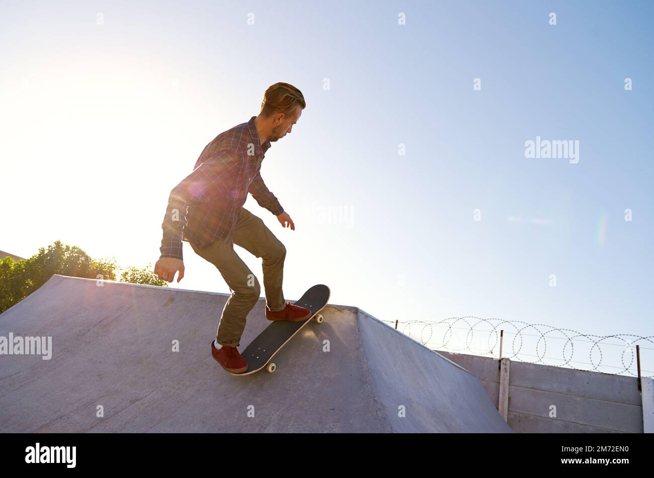 Posséder ces rampes. Un jeune homme qui fait des tours sur son skateboard au skate Park. Banque D'Images