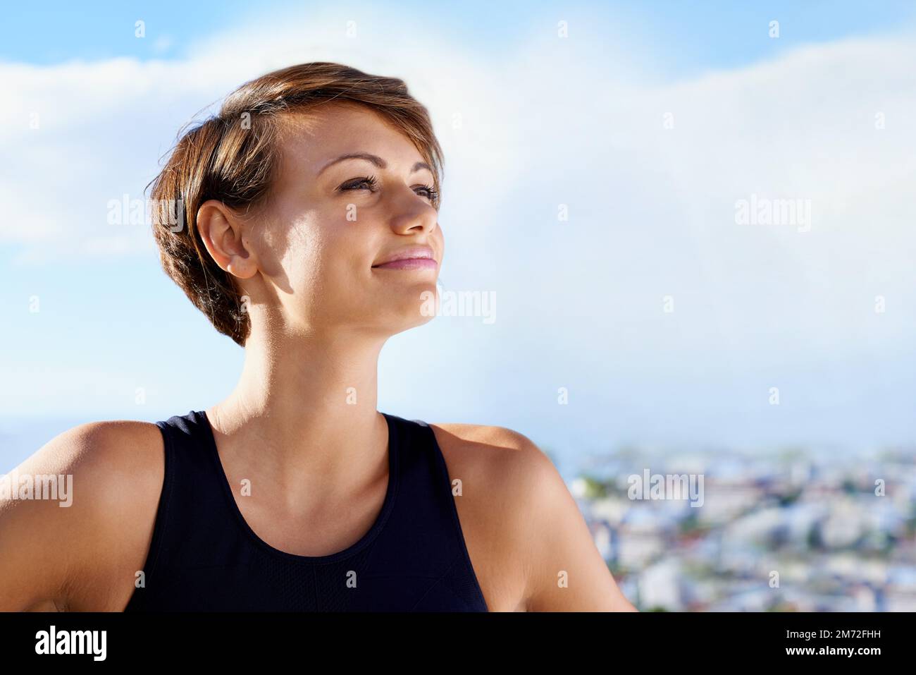 Belle journée pour une séance d'entraînement. une jeune femme souriante vêtue de vêtements d'exercice debout à l'extérieur. Banque D'Images