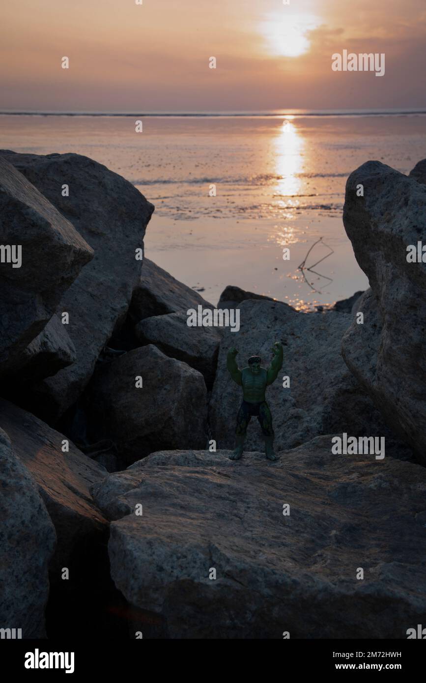 Hulk, le héros de la bande dessinée jouet était situé sur la plage rocheuse pendant l'heure du coucher du soleil Banque D'Images